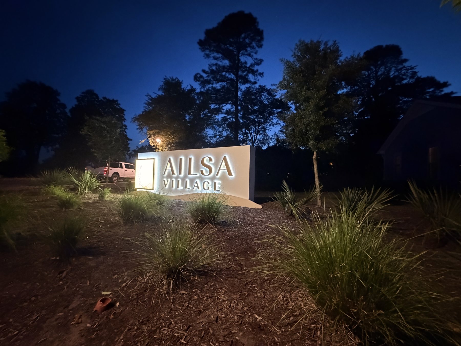 Wide night view of the Ailsa Village illuminated monument sign