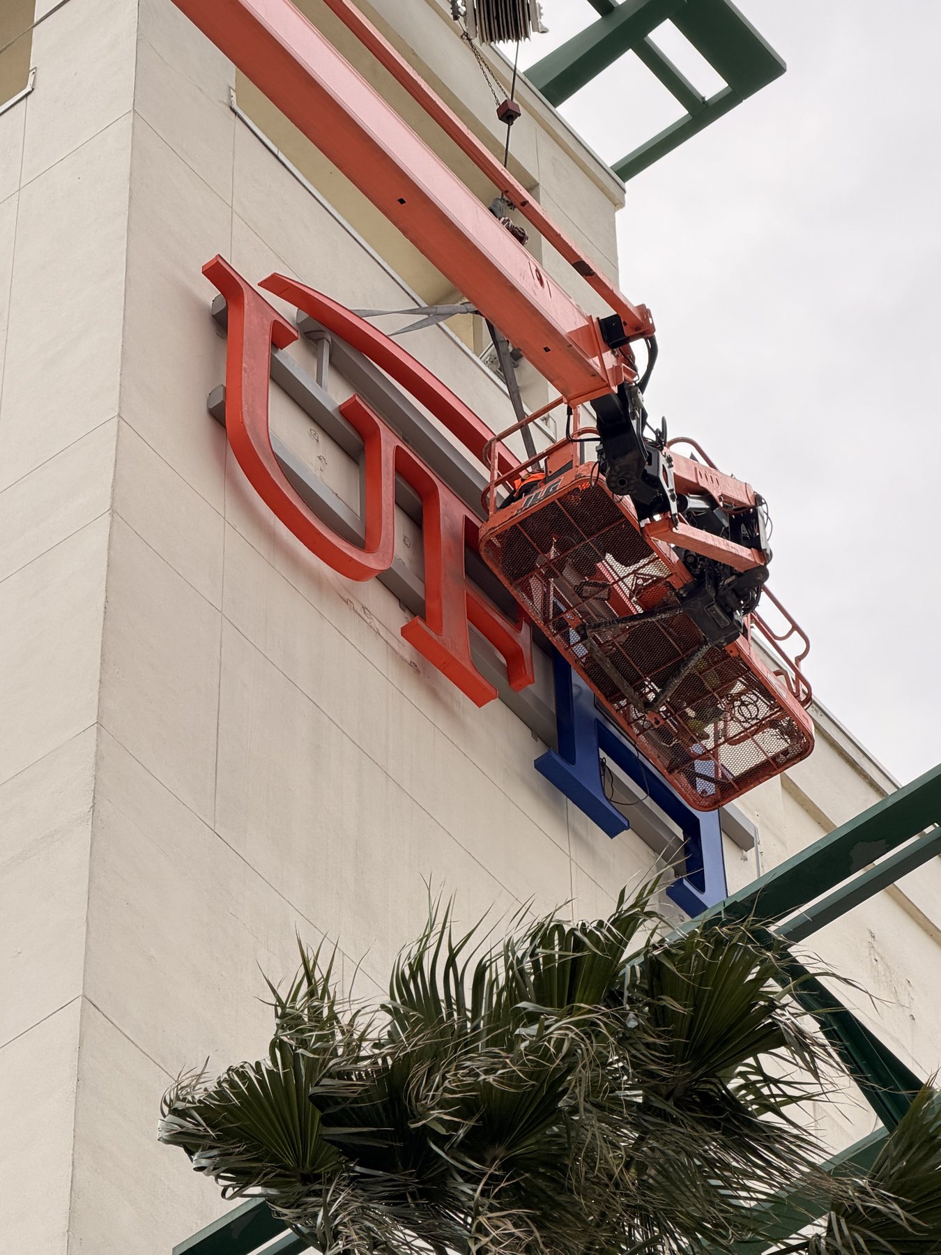Lift crew installing exterior channel letters on a commercial wall
