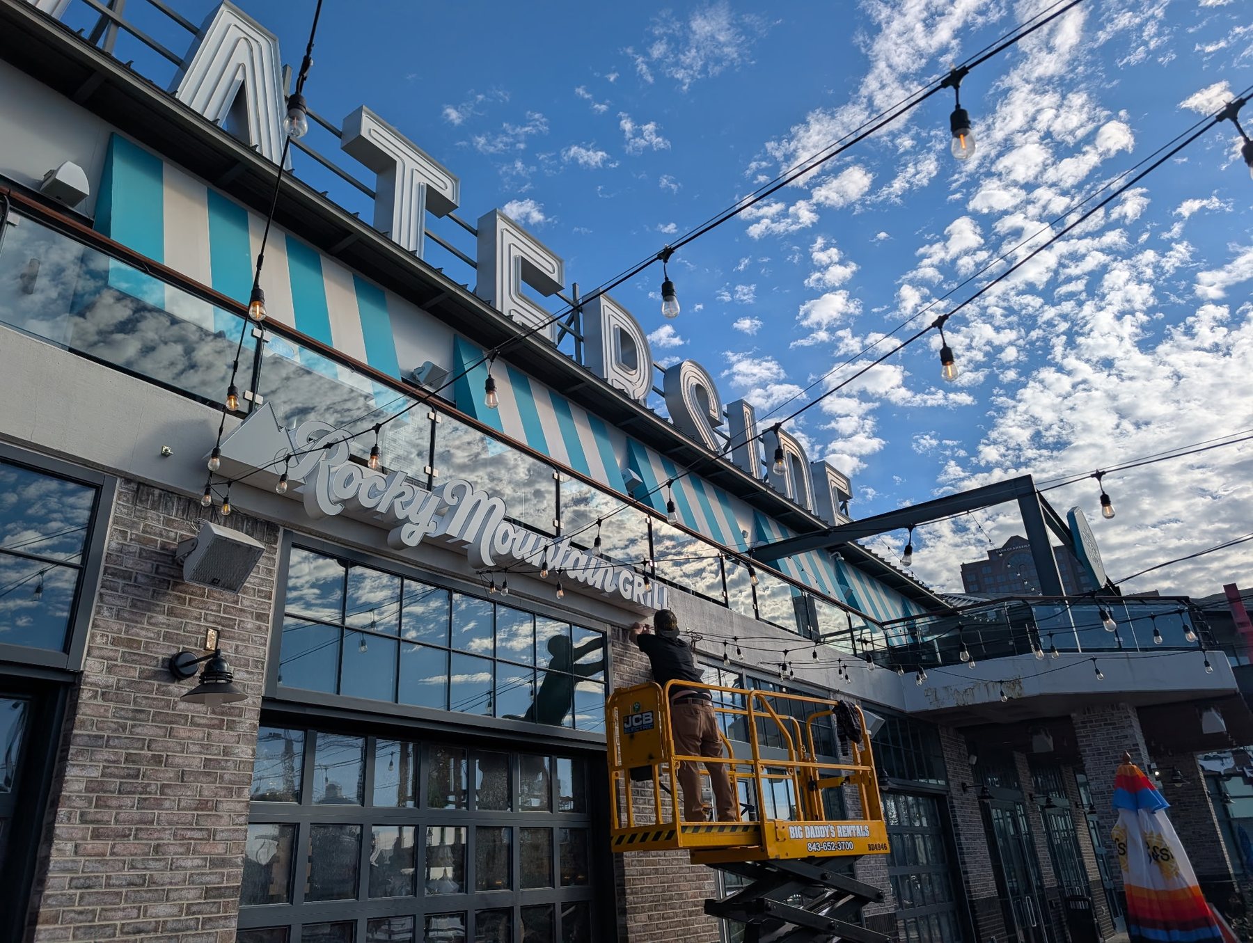 Commercial storefront sign installation with lift equipment