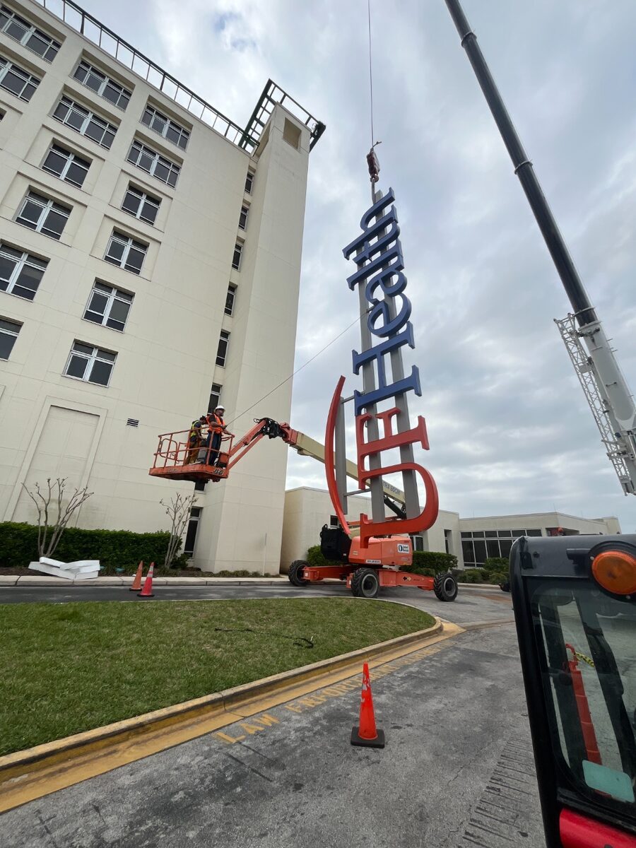 Crane hoisting large pylon sign into position
